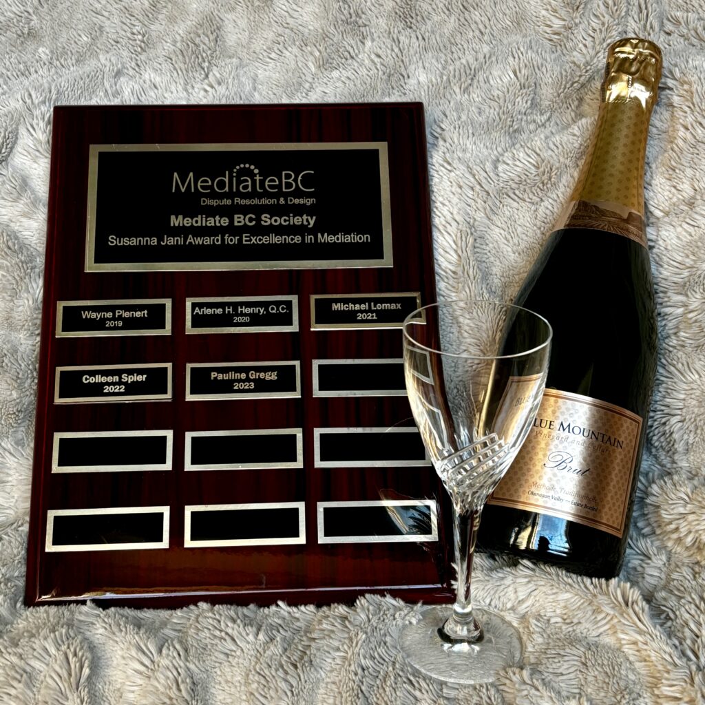 The Jani Award plaque, a crystal glass and a bottle of sparkling wine on a grey furry background.